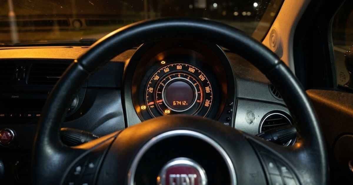 ABS warning light glowing amber alone on the instrument cluster of a 2014 Fiat 500 Lounge at night, all other warning lights off, odometer reading 67412 miles