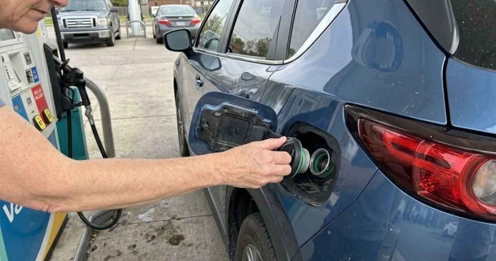 Driver checking the fuel cap on a Mazda after the check engine light came on